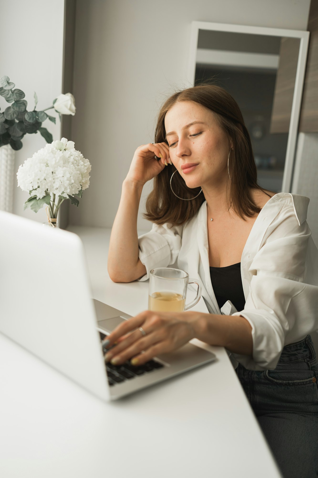 close up of young pretty woman drinking tea while break after typing and browsing online on laptop