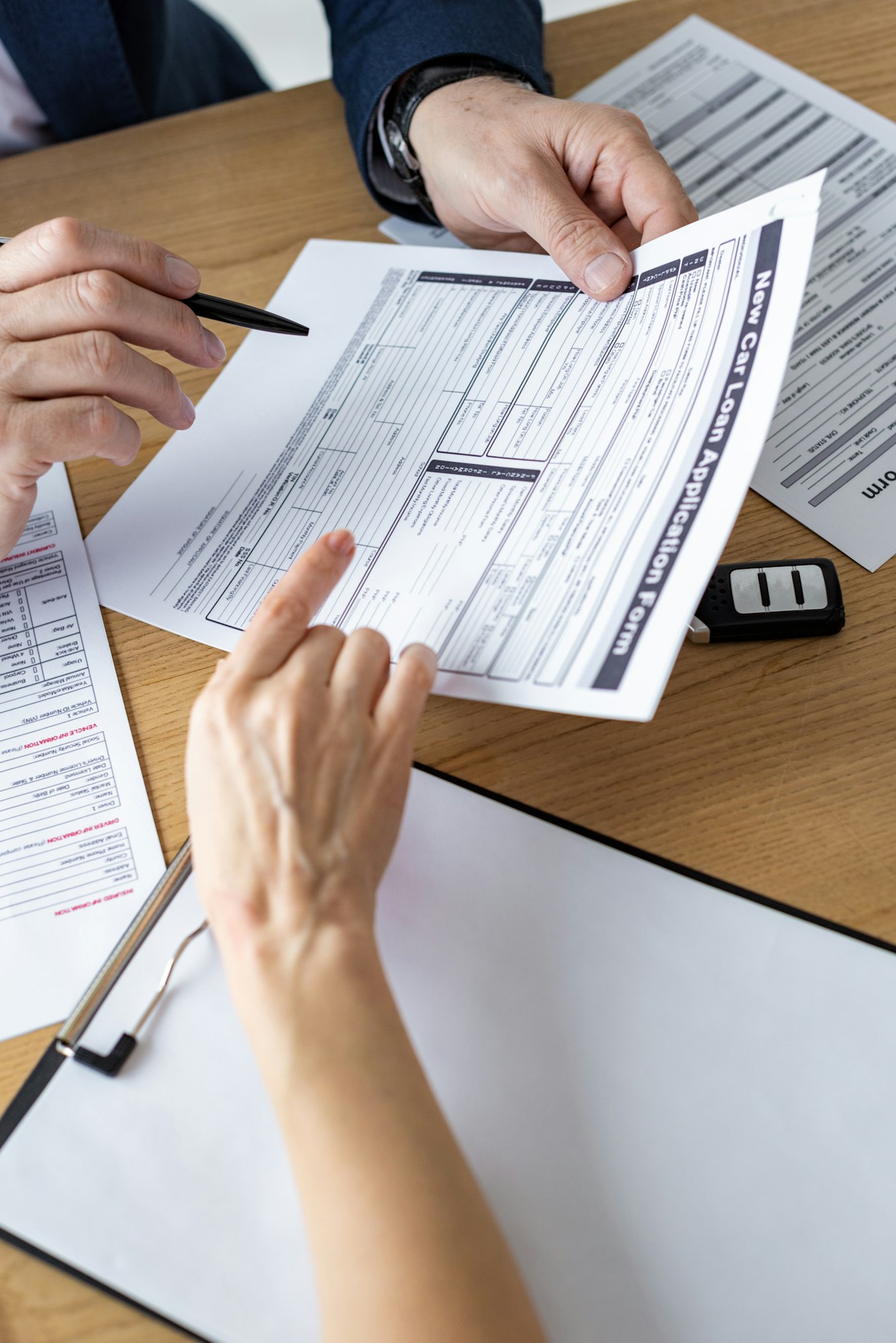 cropped view of car dealer showing car loan application form to woman in office