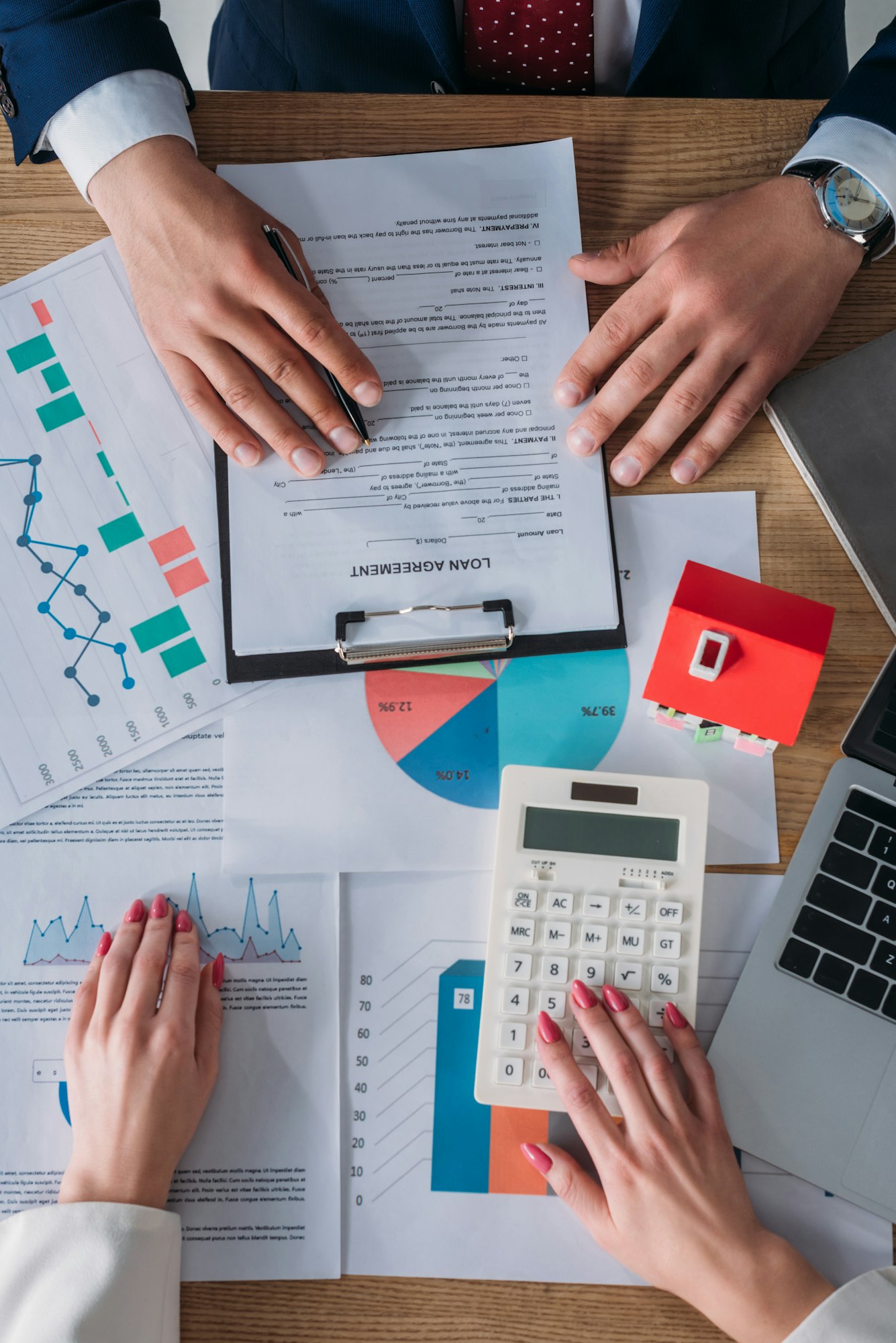 partial view of customer reading loan agreement and businesswoman using calculator while sitting at